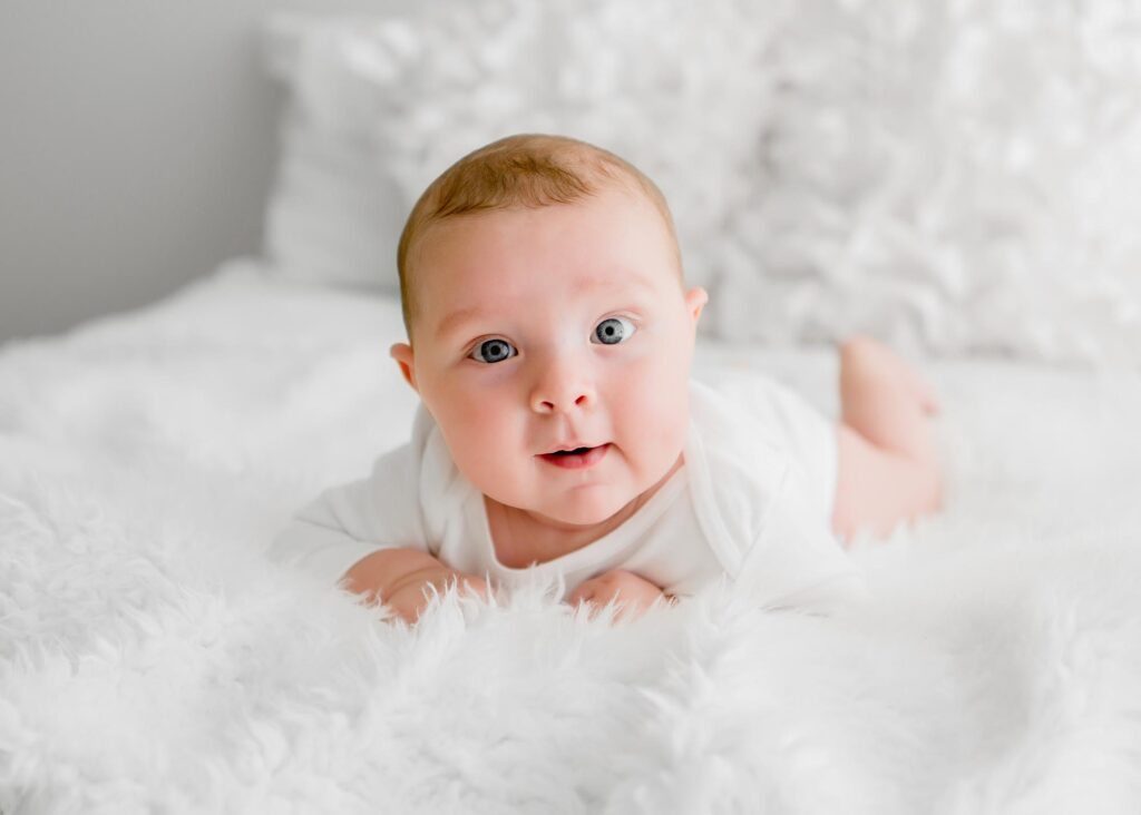 baby on all white bed photography