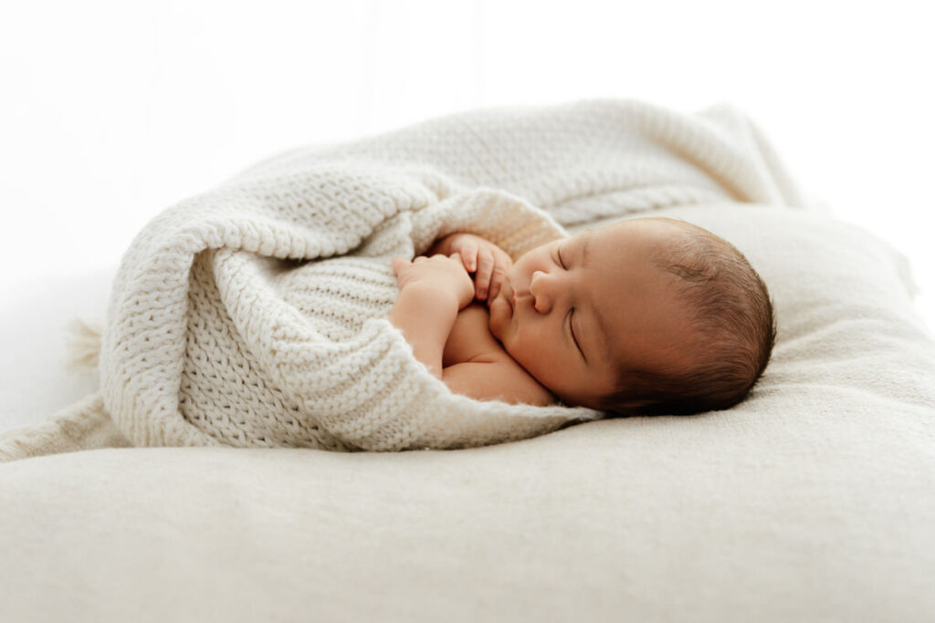 Newborn baby wrapped in a textured blanket.