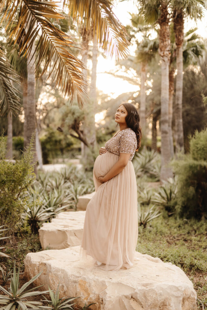 Pregnant mother posing on a large boulder rock during a maternity photo shoot at Umm Al Emarat Park in Abu Dhabi. 