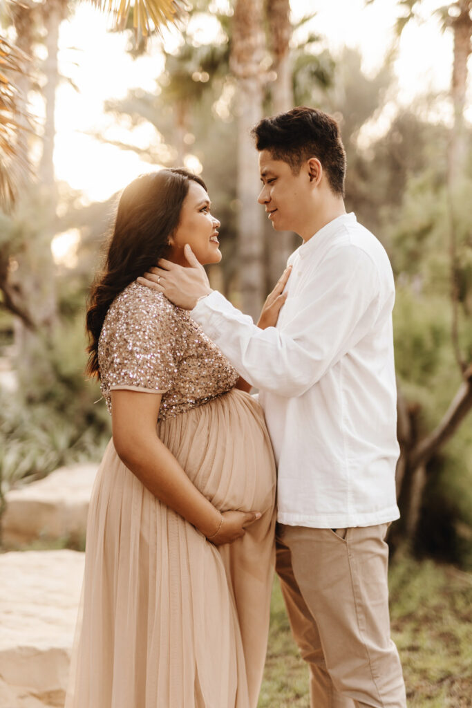 Expecting parents posing on a large boulder rock during a maternity photo shoot at Umm Al Emarat Park in Abu Dhabi. 