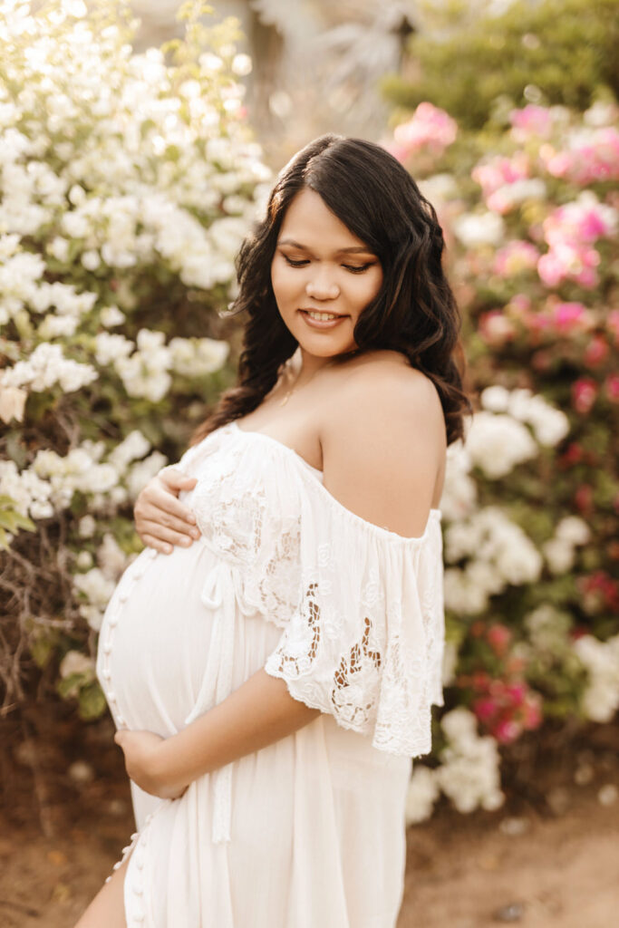 Pregnant mother posing in front of flowers during a maternity photo shoot at Umm Al Emarat Park in Abu Dhabi. 