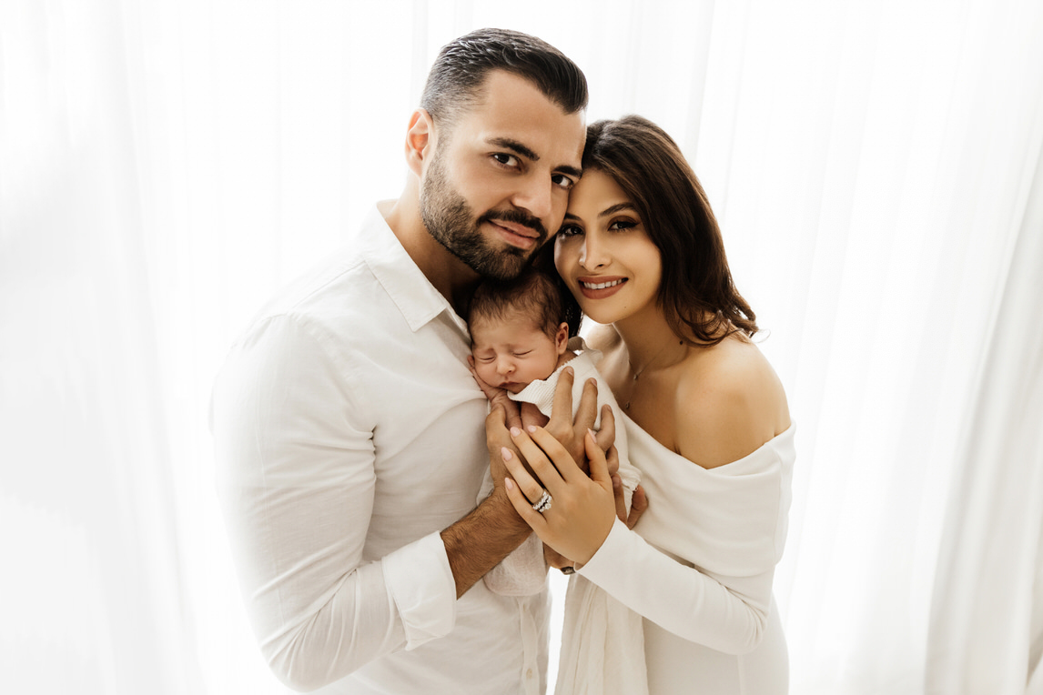 Parents holding newborn baby together during newborn baby photo shoot in Abu Dhabi, UAE.