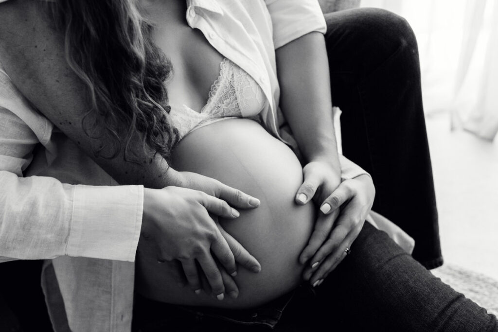 The husband's gentle touch on his wife's baby bump showcases their love and excitement for their growing family