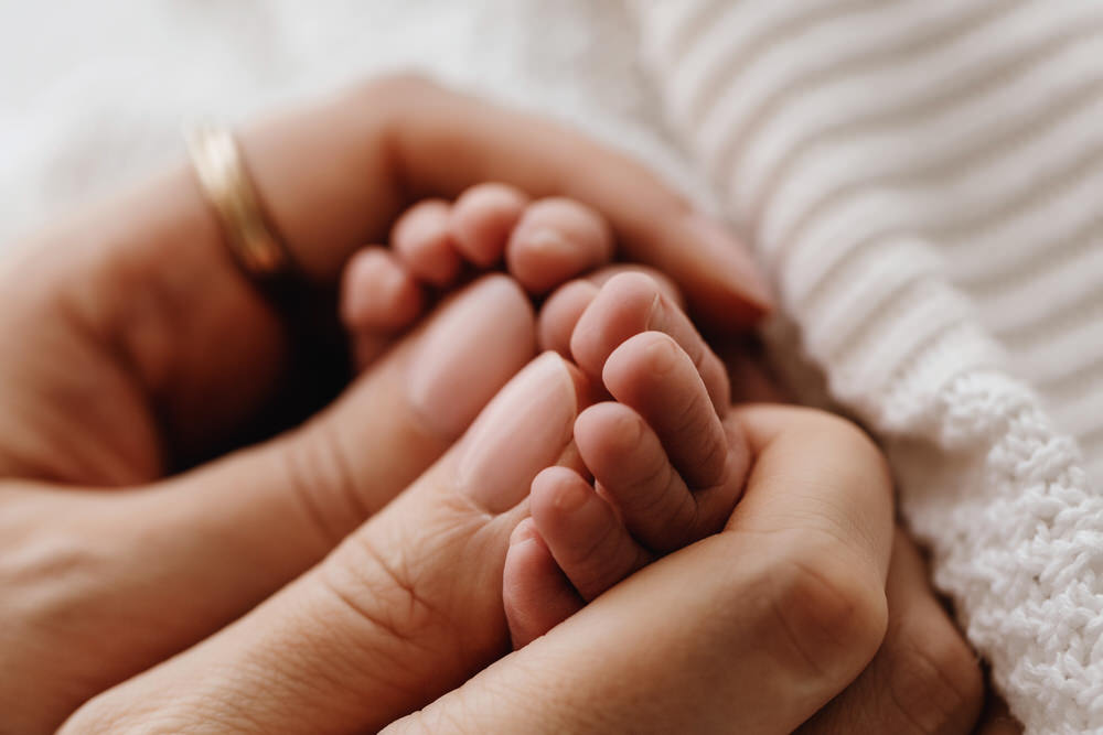 The mother is holding the newborn baby's tiny finger in Abu Dhabi